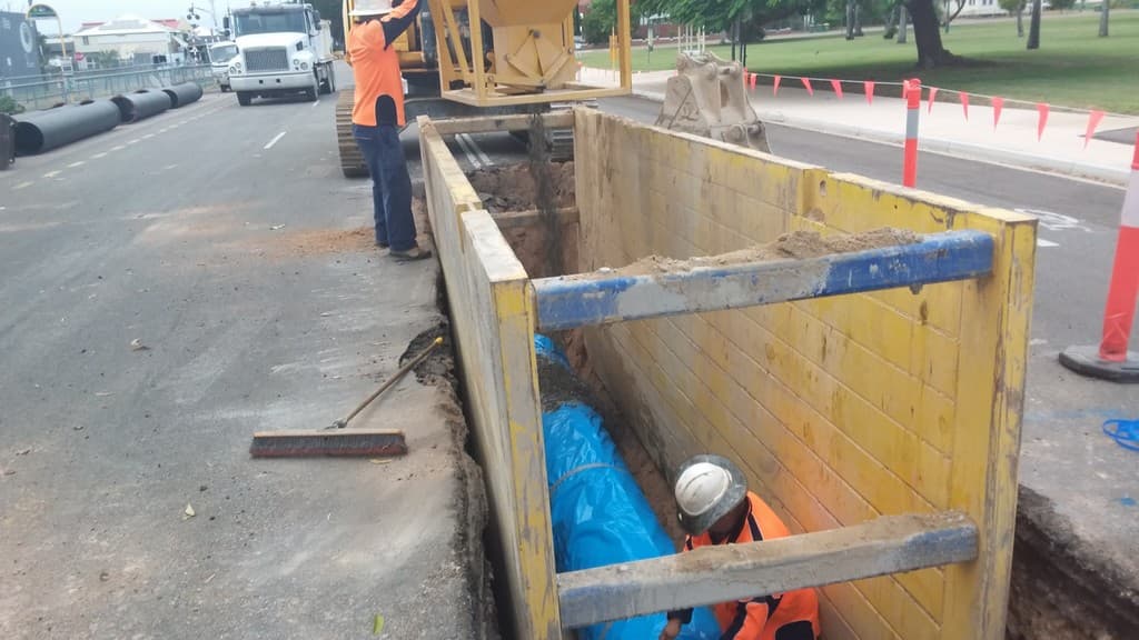 Pipe layer in a trench shield installing a new water main beside a city street