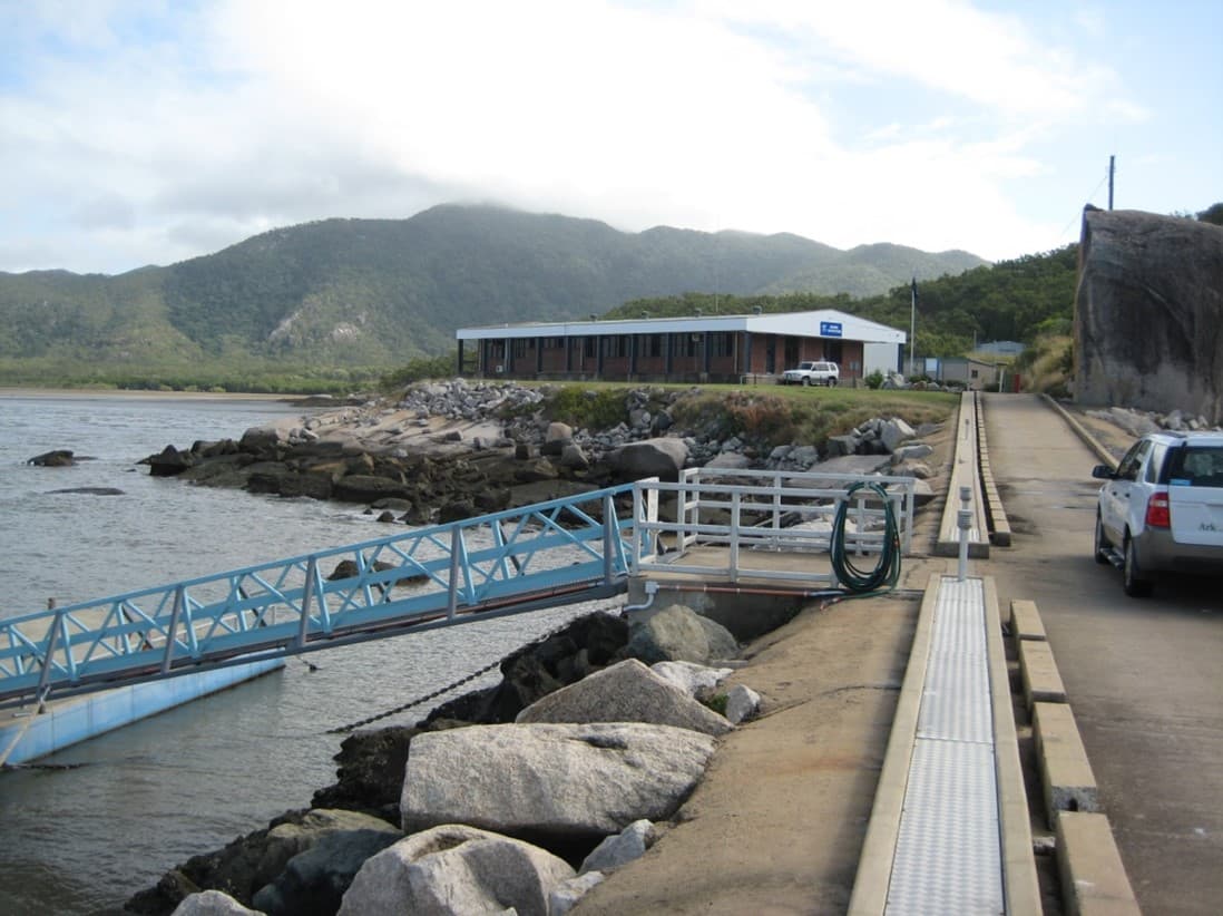 Rock breakwater, jetty and gangway at the AIMS Cape Ferguson site, with buildings and hills behind