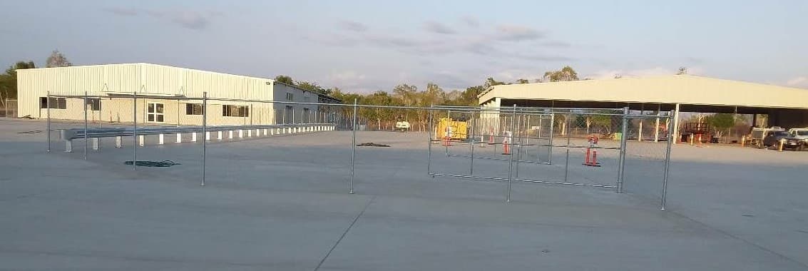 Sheds and a sealed hardstand behind temporary fencing at the Herveys Range Front resource recovery facility