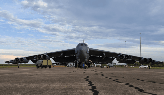 B-52 bomber parked on an airfield apron, with cracked pavement in the foreground